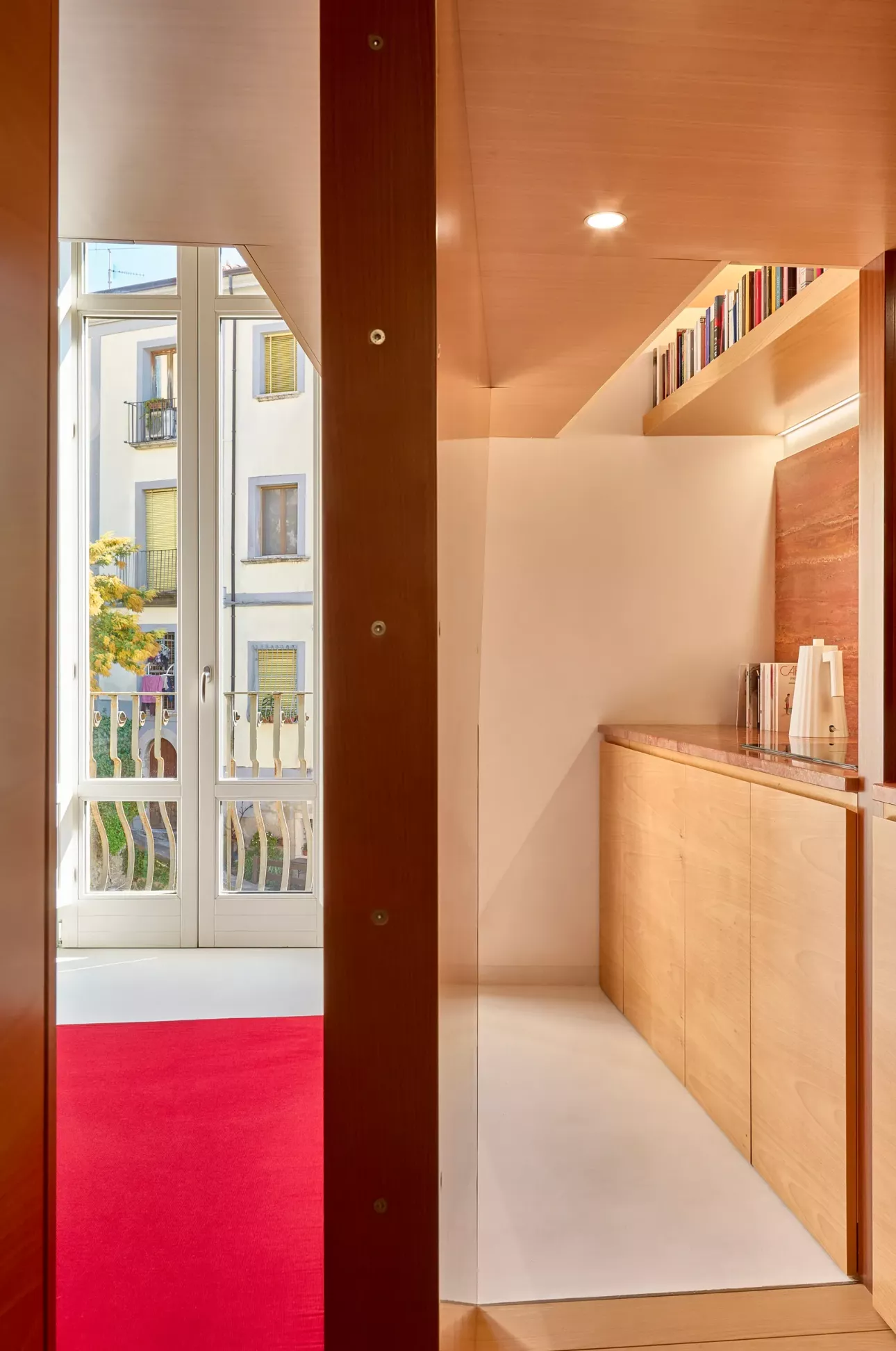 Η χειροποίητη ξύλινη κουζίνα στα δεξιά, εμώ αριστέρα η θέα ανοίγει προς το μπαλκόνι και την πλατεία/Φωτογραφία: Bruno Architetture