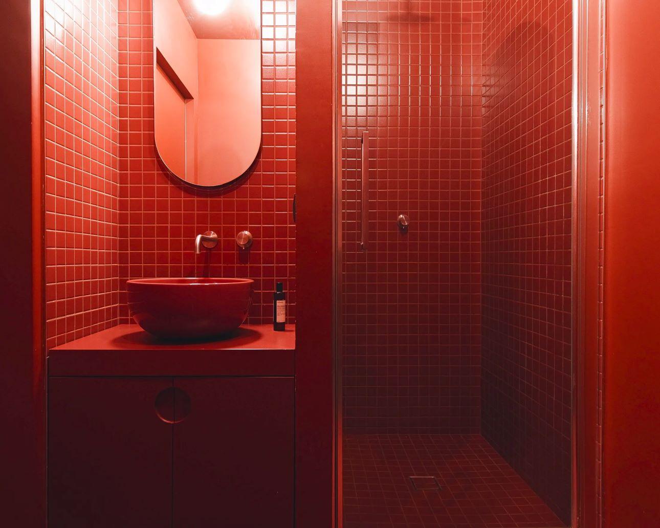 ο μπάνιο εισάγει μια δραματική αλλαγή, με κάθε επιφάνεια βαμμένη σε βαθύ κόκκινο/ Φωτογραφία: Atelierzero 