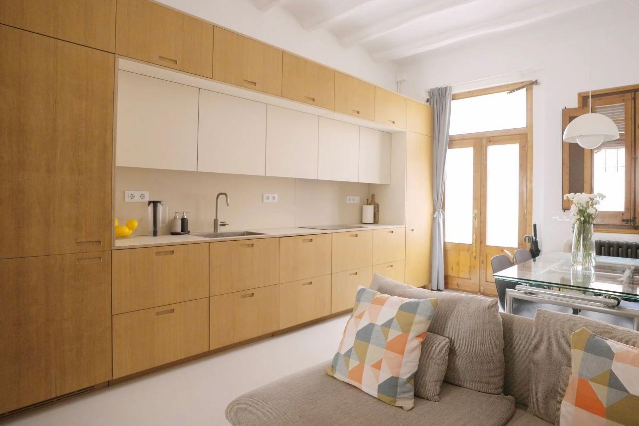 Η κουζίνα εκτείνεται σε συνεχόμενη γραμμή, ενισχύοντας το βάθος του χώρου/ Φωτογραφία: Santa Arquitectura