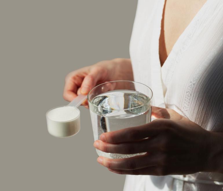 γυναίκα κρατάει συμπληρώματα διατροφής με κολλαγόνο ή πρωτόγαλα