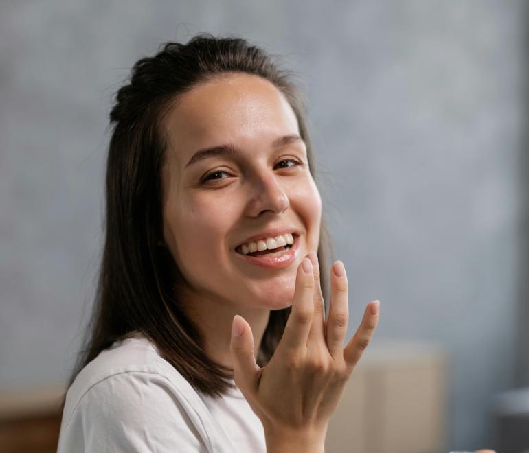 νέα γυναίκα με λευκό t-shirt που φοράει προϊόν χειλιών