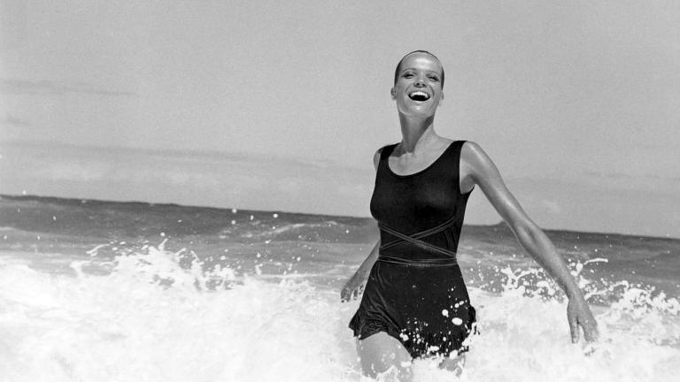 Model Veruschka walking in the surf, wearing a black knit sunsuit made of Enkalure nylon fabric, designed by Betsey Johnson for Paraphernalia. (Photo by Franco Rubartelli/Condé Nast via Getty Images)