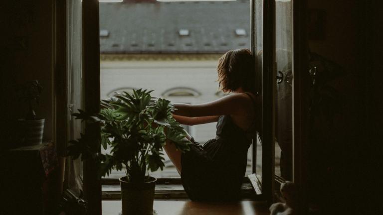 Μία γυναίκα κοιτάζει από το παράθυρό της