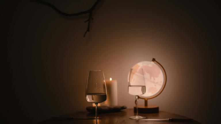 Τραπέζι με ποτήρι κρασί και ένα αναμμένο κερί