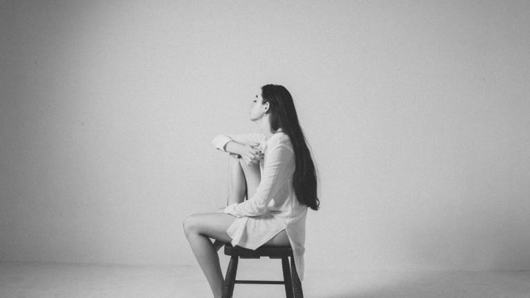 Γυναίκα που κάθεται σκεπτική σε σκαμπό 