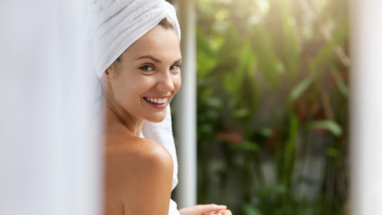 νέα γυναίκα με λευκές πετσέτες βγαίνει από το μπάνιο 