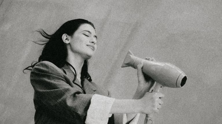 νεαρή γυναίκα φοράει σακάκι κρατάει πιστολάκι για μαλλιά ασπρόμαυρη λήψη