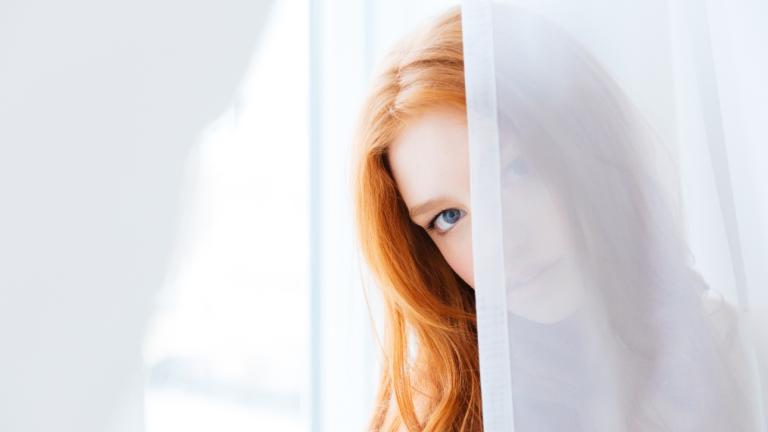 Γυναίκα πίσω από κουρτίνα/Shutterstock