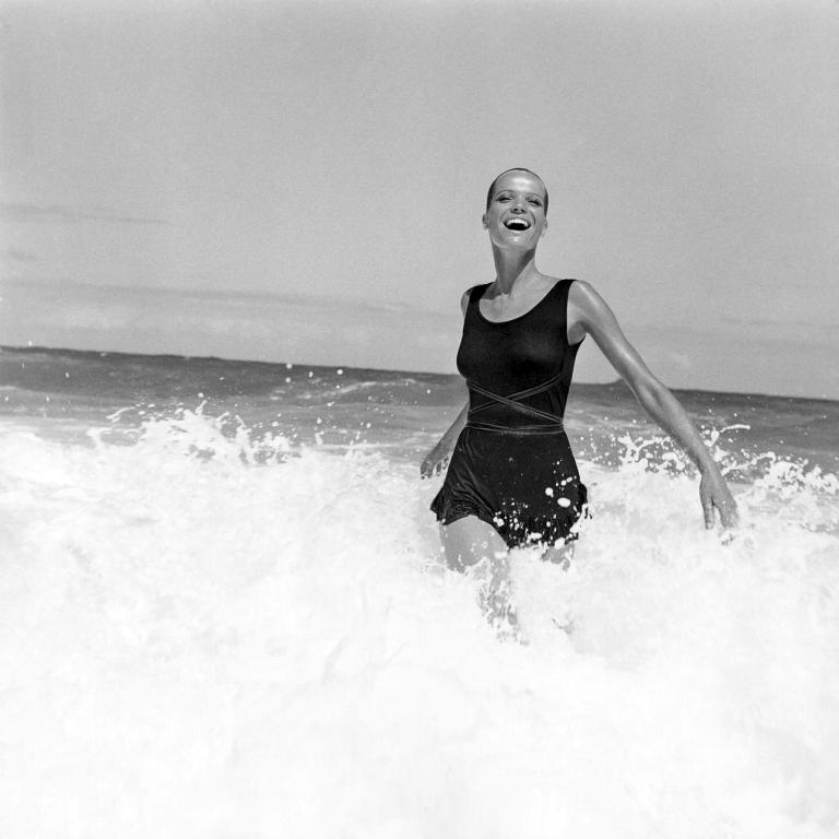 Model Veruschka walking in the surf, wearing a black knit sunsuit made of Enkalure nylon fabric, designed by Betsey Johnson for Paraphernalia. (Photo by Franco Rubartelli/Condé Nast via Getty Images)