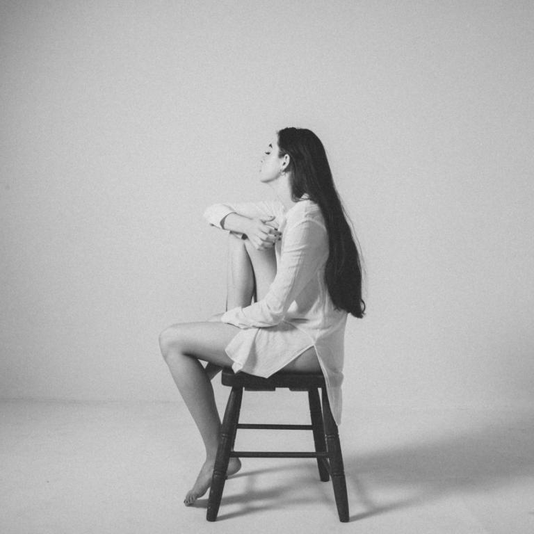 Γυναίκα που κάθεται σκεπτική σε σκαμπό 