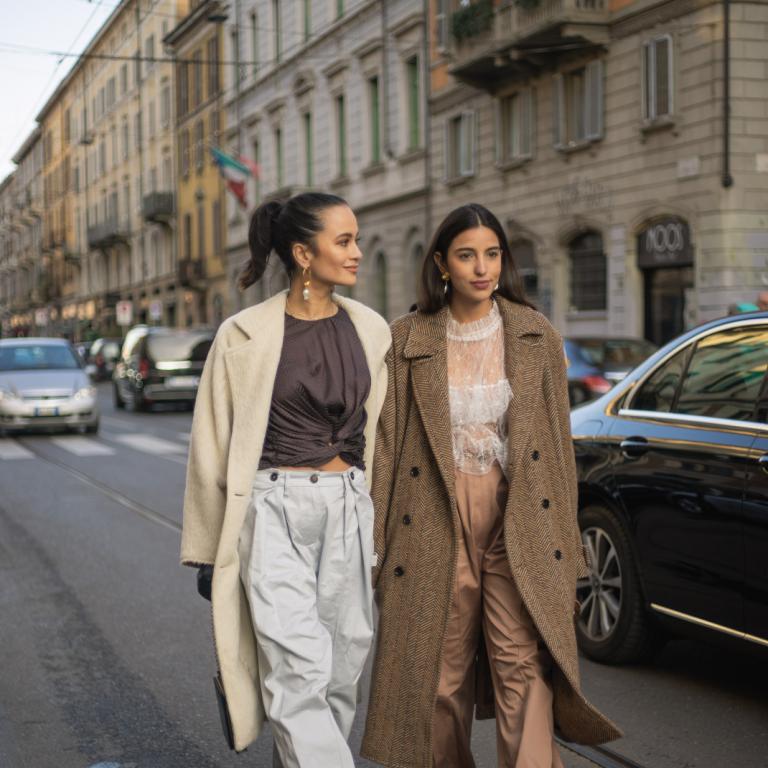 γυναίκες με παλτό και τοπ περπατούν στην εβδομάδα μόδας